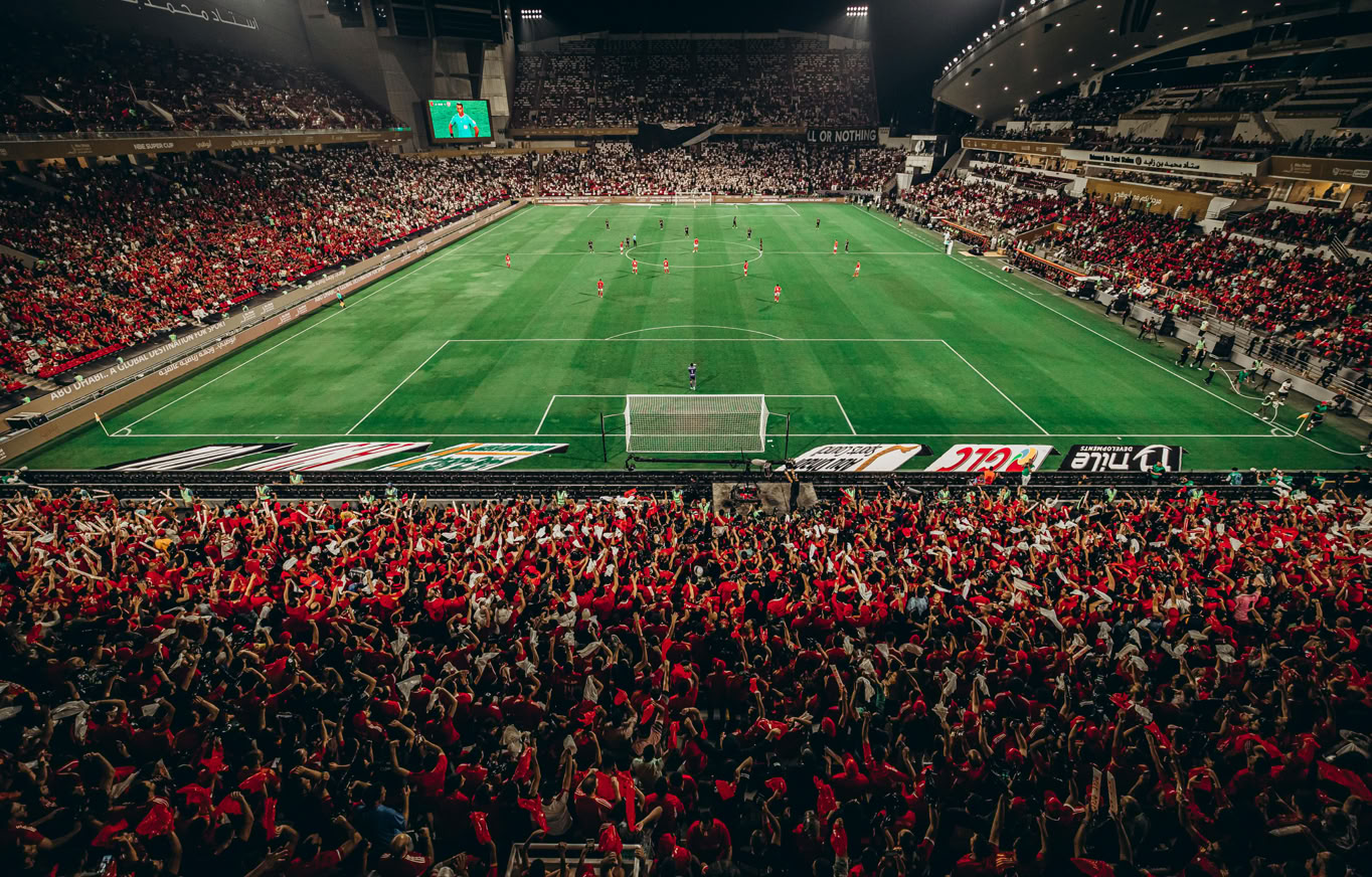 A thrilling nighttime football match with a vibrant crowd in Abu Dhabi stadium.